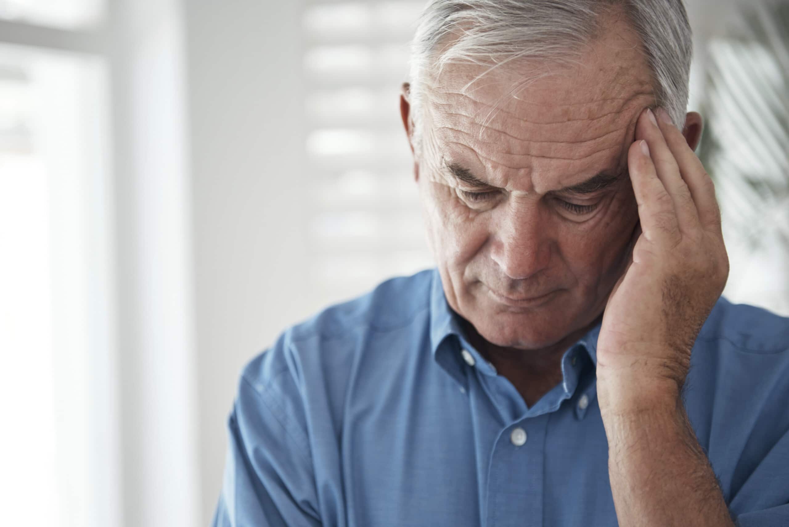 Older man rubbing forehead in pain