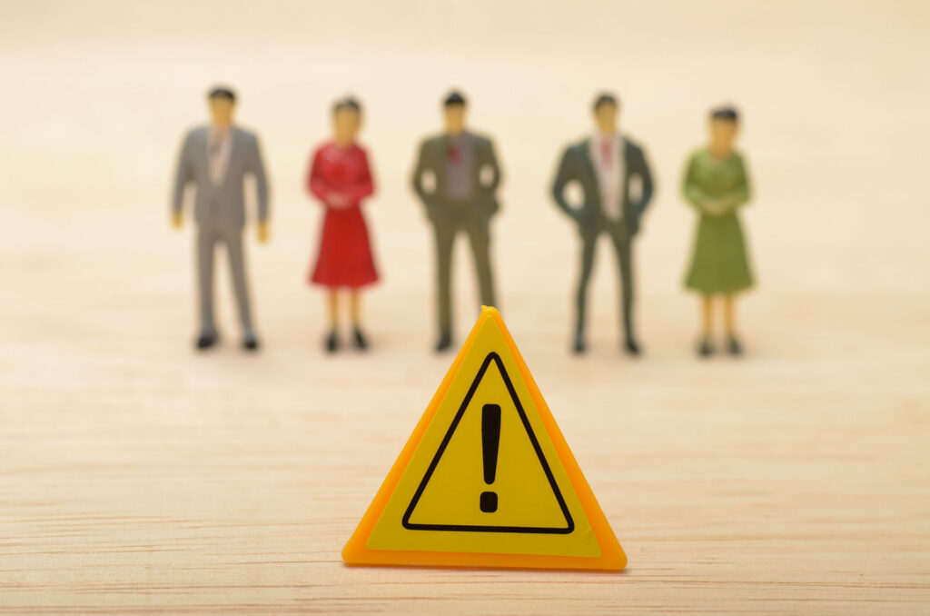 A yellow warning sign in front of a blurred group of people